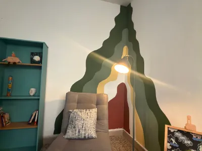 Consultorio con una butaca gris, una estantería turquesa y un mural de colores en la pared