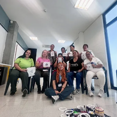 Grupo de personas sonriendo durante un taller con una psicóloga sentada en el suelo
