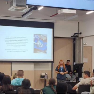Psicóloga dando un taller ante un grupo de personas con una presentación proyectada
